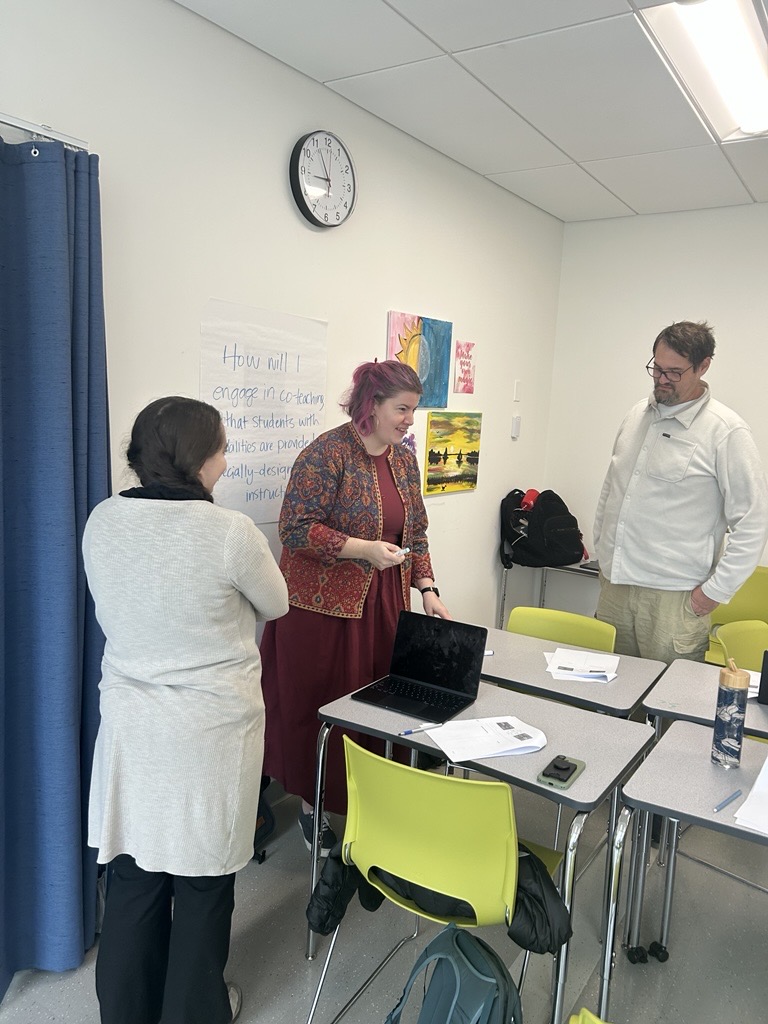 educators working together around desks with a laptop