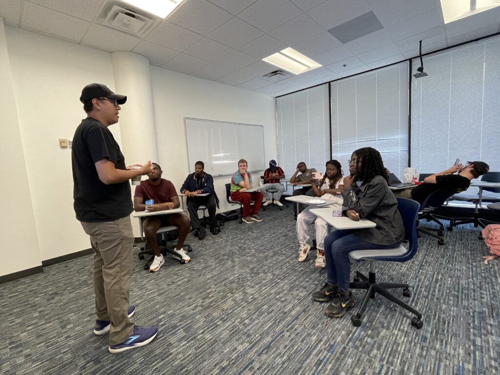 Tim standing in a classroom in front of a room full of IDEAL student sitting in desks