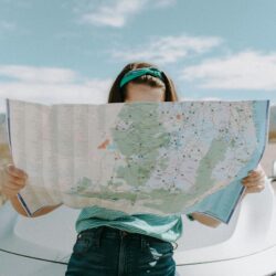 someone learning on the hood of their car looking at a map